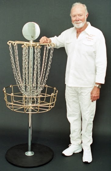 Steady" Ed Headrick the father of disc golf and invented of the the first disc golf baskets poses for a disc golf hall of fame photo next to a custom gold plated DGA Mach 3 Basket.